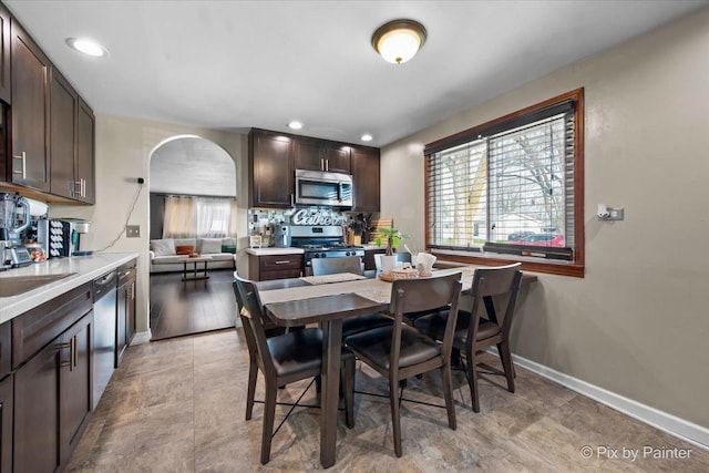dining area with baseboards, arched walkways, and recessed lighting