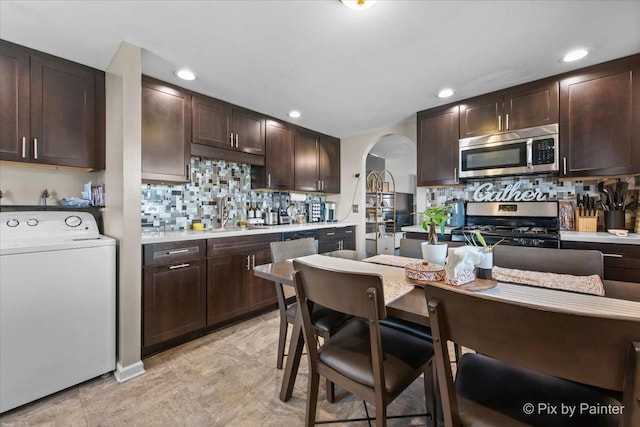 kitchen with washer / clothes dryer, appliances with stainless steel finishes, dark brown cabinets, and a sink