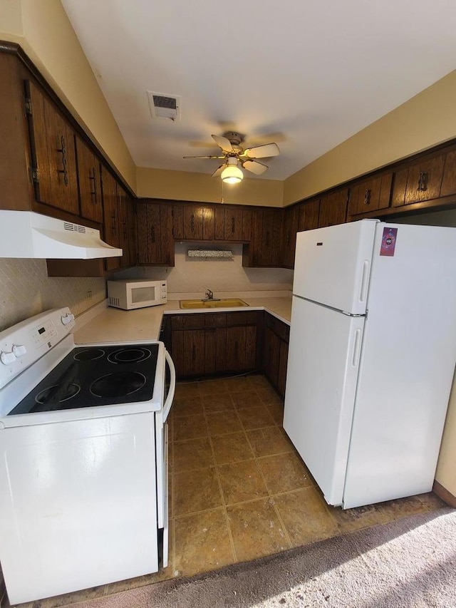 kitchen with white appliances, light countertops, under cabinet range hood, visible vents, and a sink