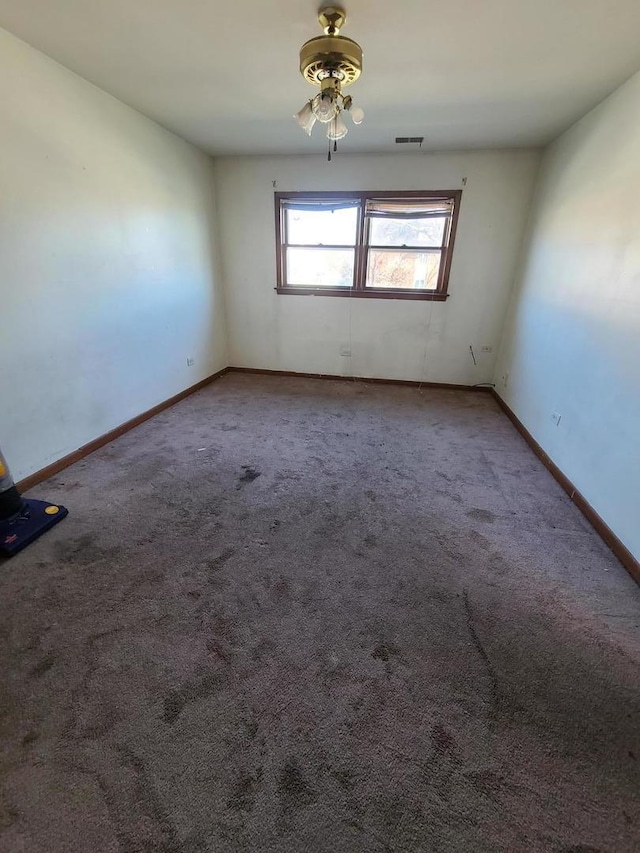 carpeted empty room featuring visible vents, baseboards, and ceiling fan