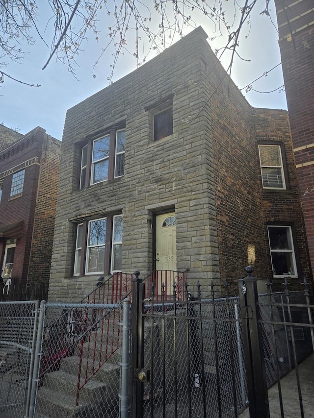 view of front of property featuring stone siding, a gate, and a fenced front yard