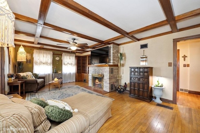 living area featuring a fireplace, a ceiling fan, visible vents, hardwood / wood-style floors, and coffered ceiling