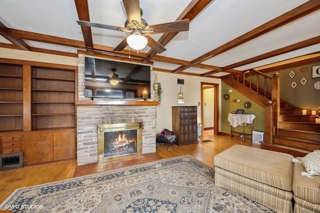 living room with beamed ceiling, a ceiling fan, visible vents, and stairway