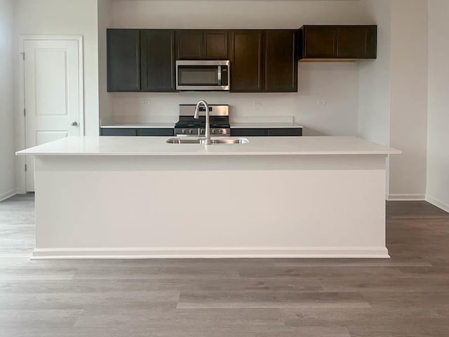 279 Charlestowne Lakes Dr, Saint Charles, IL 60174 - kitchen featuring stainless steel microwave, baseboards, a kitchen island with sink, light wood finished floors, and a sink