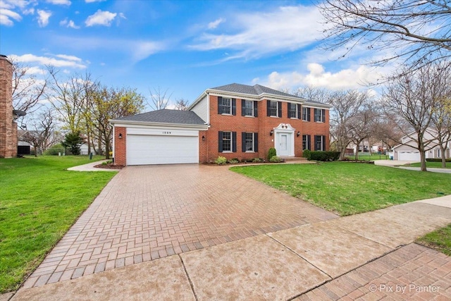 colonial inspired home featuring a garage, brick siding, a front yard, and decorative driveway