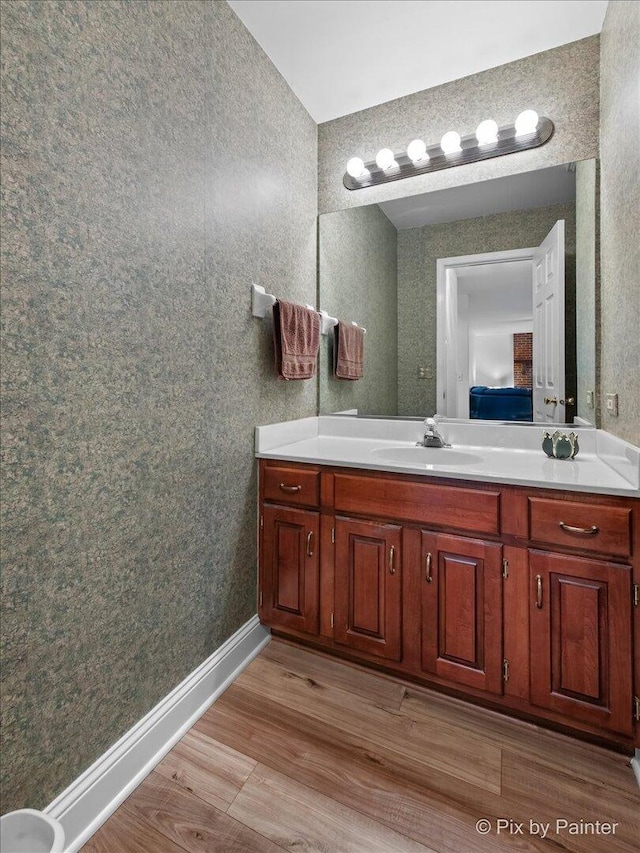 bathroom featuring baseboards, wood finished floors, ensuite bath, and vanity