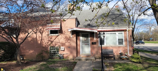 view of front of house with a shingled roof and brick siding