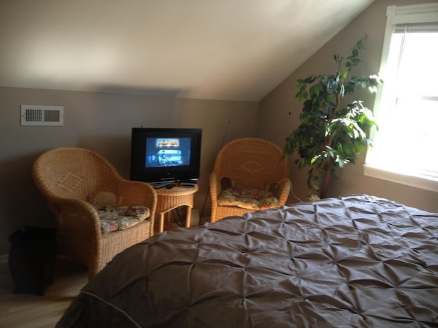 bedroom featuring visible vents, wood finished floors, and lofted ceiling