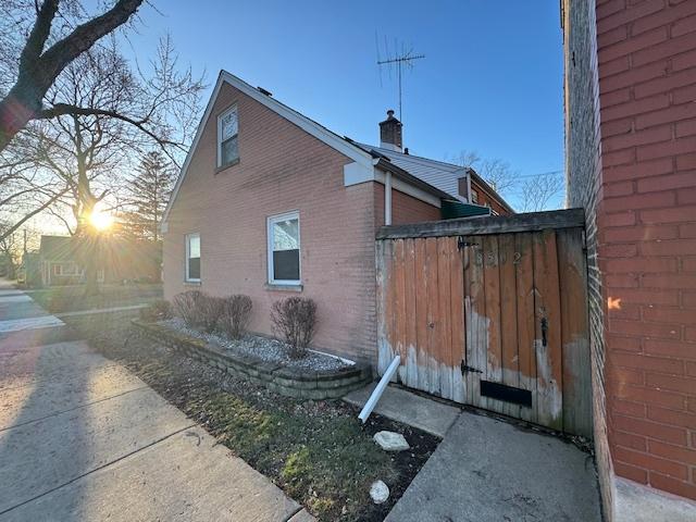 view of home's exterior with brick siding and a chimney
