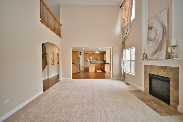 1866 Snead St, Bolingbrook, IL 60490 - unfurnished living room with arched walkways, baseboards, a tiled fireplace, and dark carpet
