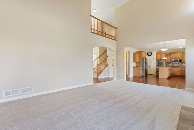 1866 Snead St, Bolingbrook, IL 60490 - unfurnished living room featuring visible vents, arched walkways, baseboards, and dark carpet