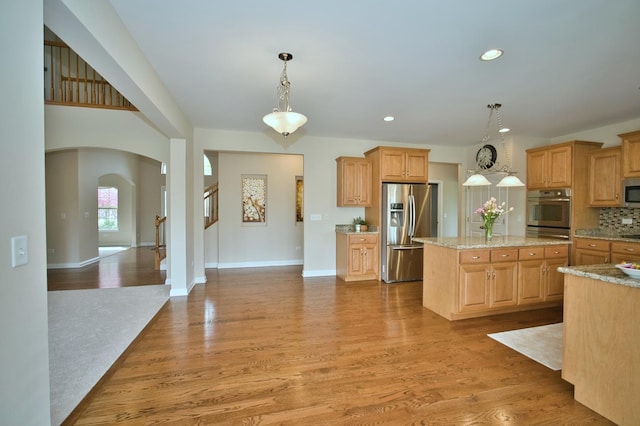 1866 Snead St, Bolingbrook, IL 60490 - kitchen featuring a kitchen island, backsplash, arched walkways, stainless steel appliances, and light wood-style flooring