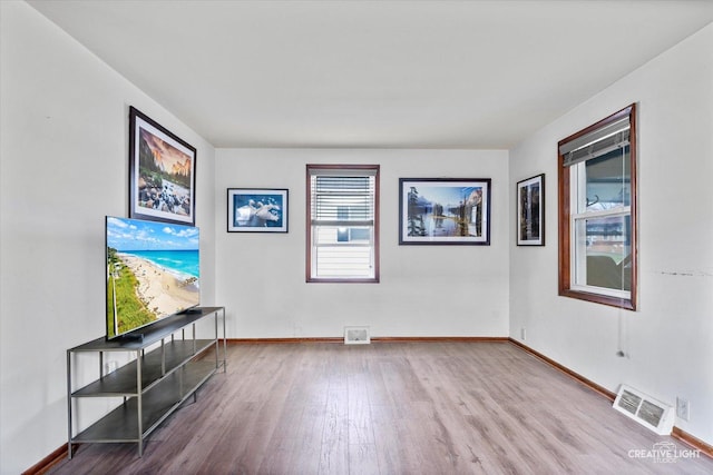 spare room featuring baseboards, wood finished floors, and visible vents