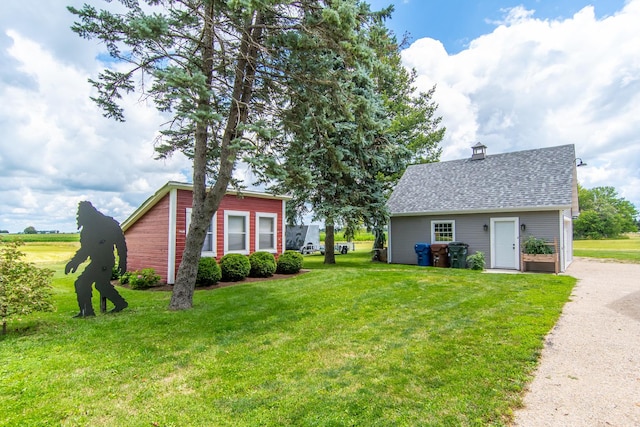 exterior space with a chimney, a shingled roof, and a yard