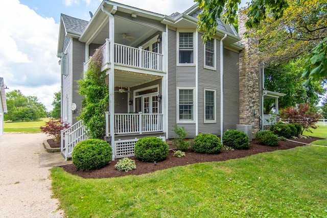 exterior space featuring a front yard, a ceiling fan, and a balcony