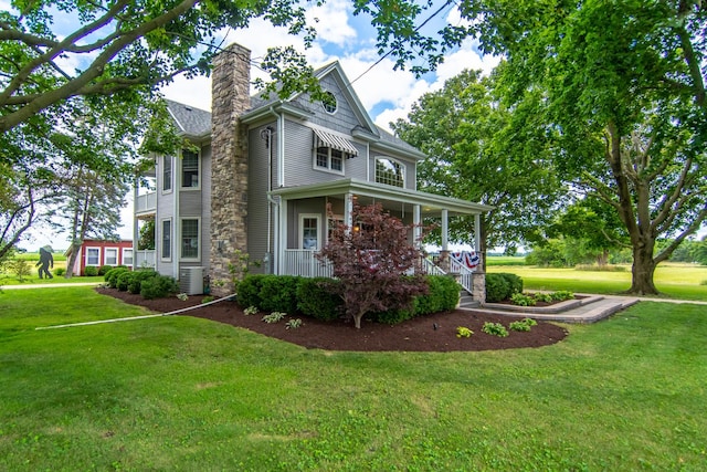 view of home's exterior with cooling unit, a lawn, covered porch, and a chimney