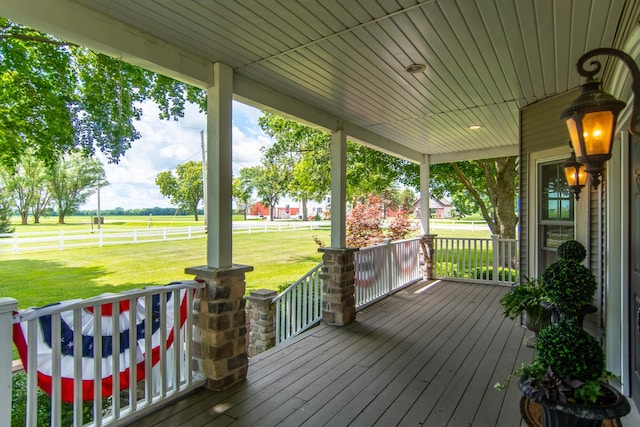 wooden terrace with a yard, covered porch, and fence