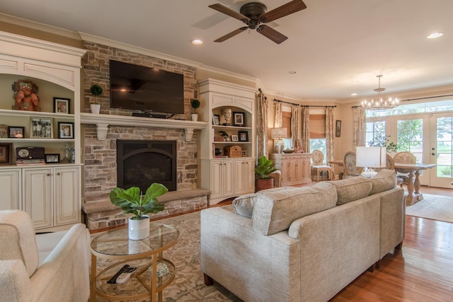 living room featuring ceiling fan, recessed lighting, ornamental molding, wood finished floors, and a stone fireplace