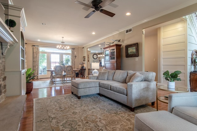 living area with recessed lighting, wood finished floors, ceiling fan with notable chandelier, visible vents, and crown molding