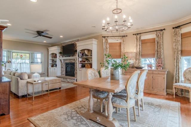 dining room with a healthy amount of sunlight, light wood finished floors, a fireplace, and crown molding