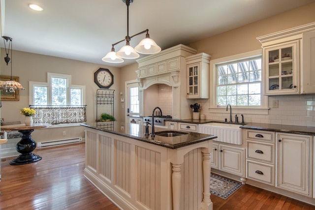 kitchen featuring baseboard heating, cream cabinets, dark wood-type flooring, and a sink