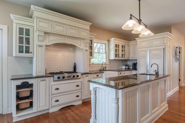 kitchen with stainless steel gas cooktop, wood finished floors, decorative backsplash, and a sink