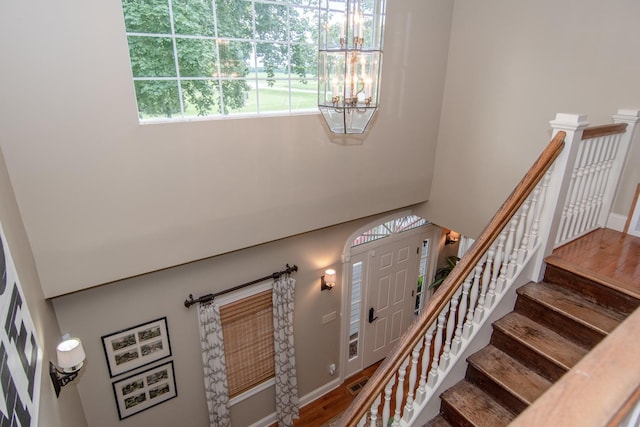 stairs featuring baseboards, visible vents, wood finished floors, and an inviting chandelier