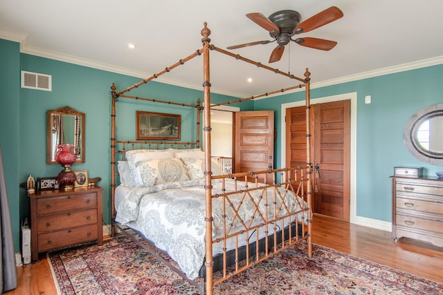 bedroom with ornamental molding, visible vents, wood finished floors, and baseboards