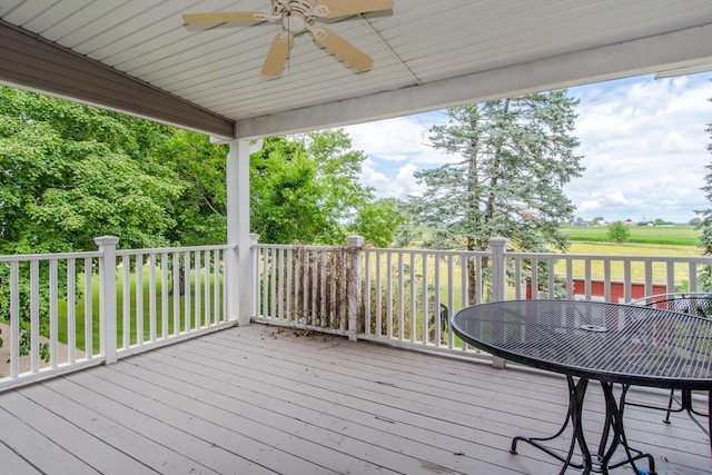 wooden terrace with outdoor dining area and a ceiling fan