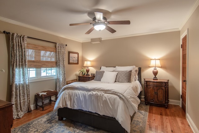 bedroom with wood finished floors, ceiling fan, ornamental molding, and baseboards
