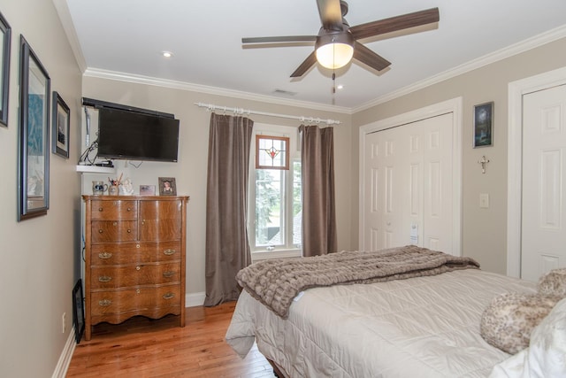 bedroom featuring light wood-style floors, crown molding, a ceiling fan, visible vents, and baseboards