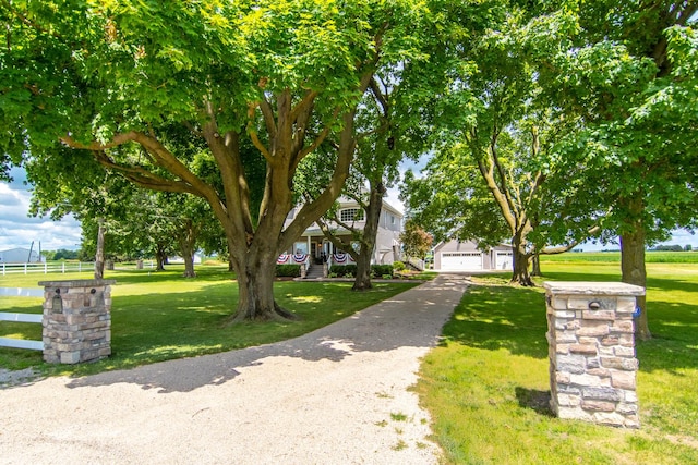 obstructed view of property featuring a detached garage and a front lawn