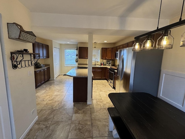 800 Tomahawk Trl, Round Lake Heights, IL 60073 - kitchen with dark brown cabinetry, a center island, a sink, hanging light fixtures, and stainless steel appliances