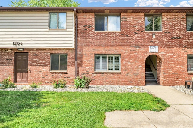 townhome / multi-family property featuring a front lawn and brick siding