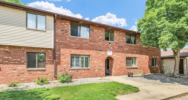 view of property featuring brick siding and a front yard