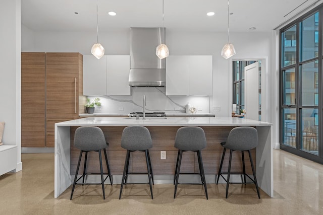 kitchen with wall chimney exhaust hood, modern cabinets, white cabinetry, light countertops, and decorative light fixtures