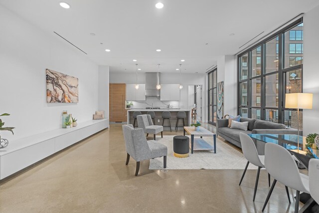 living area featuring finished concrete floors, a wall of windows, and recessed lighting
