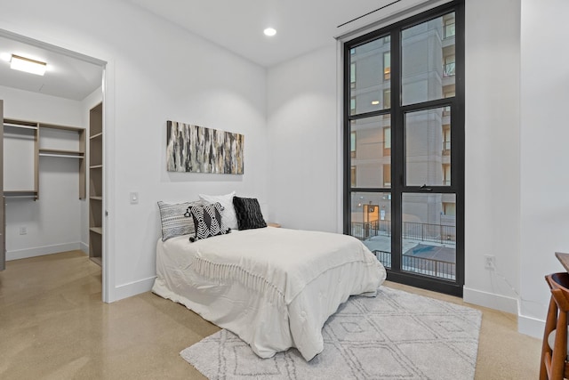 bedroom featuring baseboards, a walk in closet, and recessed lighting