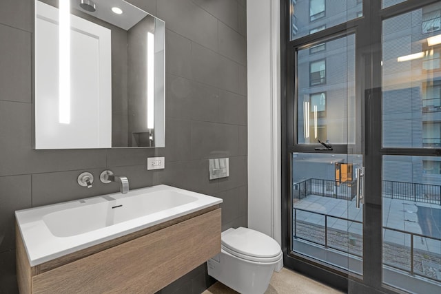 bathroom featuring toilet, a sink, and tile walls