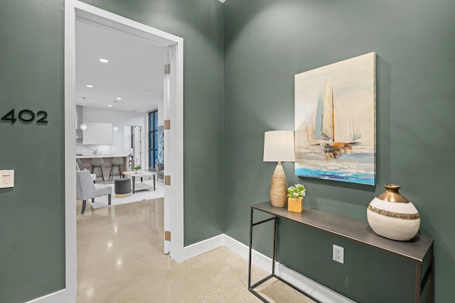 corridor with concrete floors, baseboards, and recessed lighting