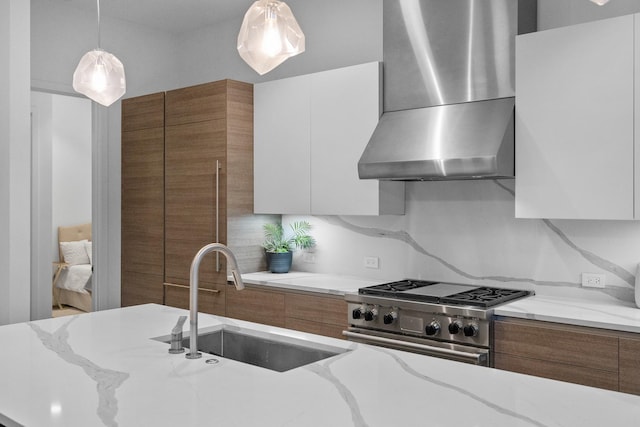 kitchen featuring wall chimney exhaust hood, modern cabinets, a sink, high end stainless steel range oven, and brown cabinets