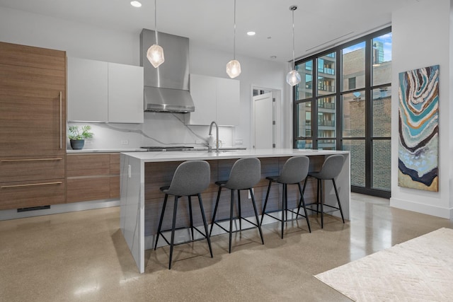 kitchen with wall chimney range hood, white cabinets, modern cabinets, and light countertops