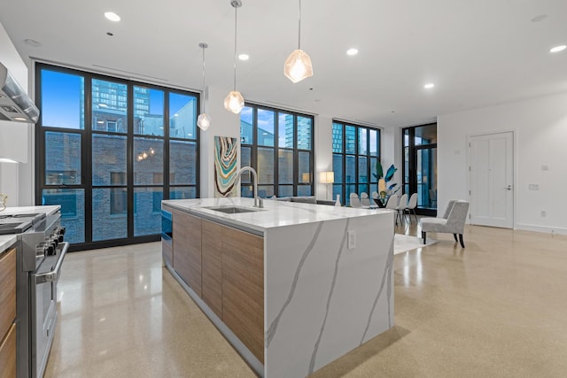 kitchen with modern cabinets, stainless steel range, a sink, a wall of windows, and light stone counters