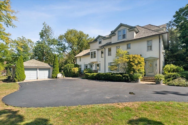 view of front of home with an outdoor structure, a detached garage, and stucco siding