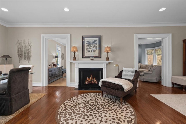 sitting room with a fireplace with flush hearth, recessed lighting, ornamental molding, and dark wood-style flooring