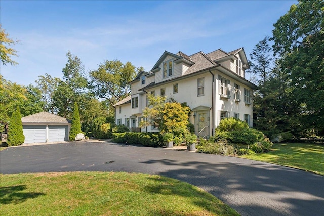 view of side of property featuring stucco siding, an outdoor structure, a yard, and a garage