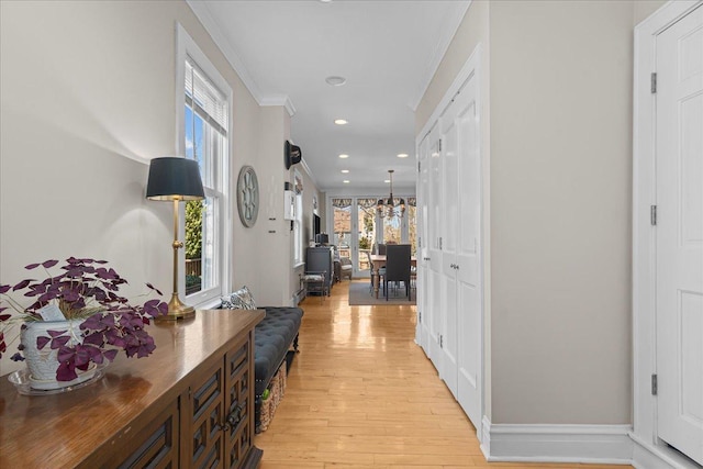 corridor featuring an inviting chandelier, light wood finished floors, baseboards, ornamental molding, and recessed lighting