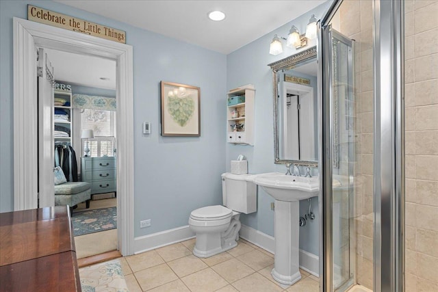 full bathroom featuring a shower stall, tile patterned floors, toilet, a sink, and baseboards