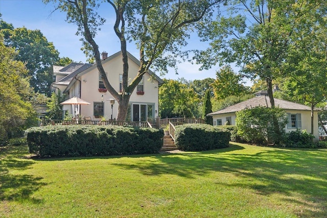 back of property featuring a lawn, a deck, and stucco siding
