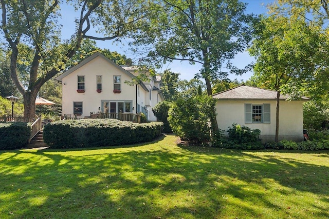 exterior space featuring stucco siding, a wooden deck, and a lawn